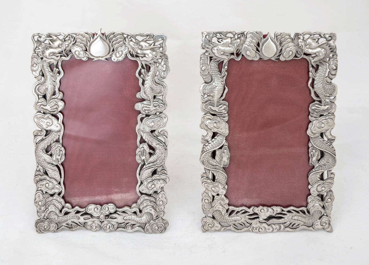 A pair of Chinese export silver photo frames, each with a border of two coiled opposing dragons separated by a flaming pearl, and with the easel supports engraved to simulate bamboo.  The frames were made by the well known Hong Kong firm of Wang