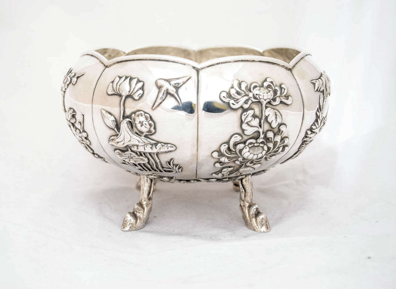 A Chinese export silver bowl marked KMS for Kwong Man Shing, who was making and selling in Hong Kong in the late 19th and early 20th century. The eight panels are applied with foliage and birds and the bowl stands on four legs modelled as