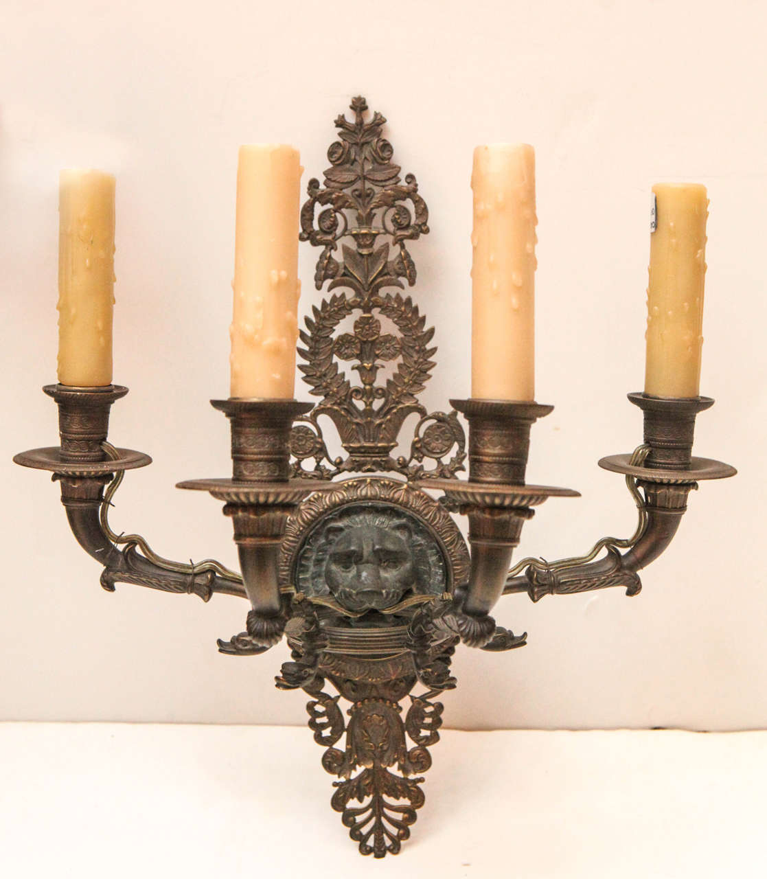 Two hand-cast electrified French wall sconces with intricate, foliate motifs and lion medallions.