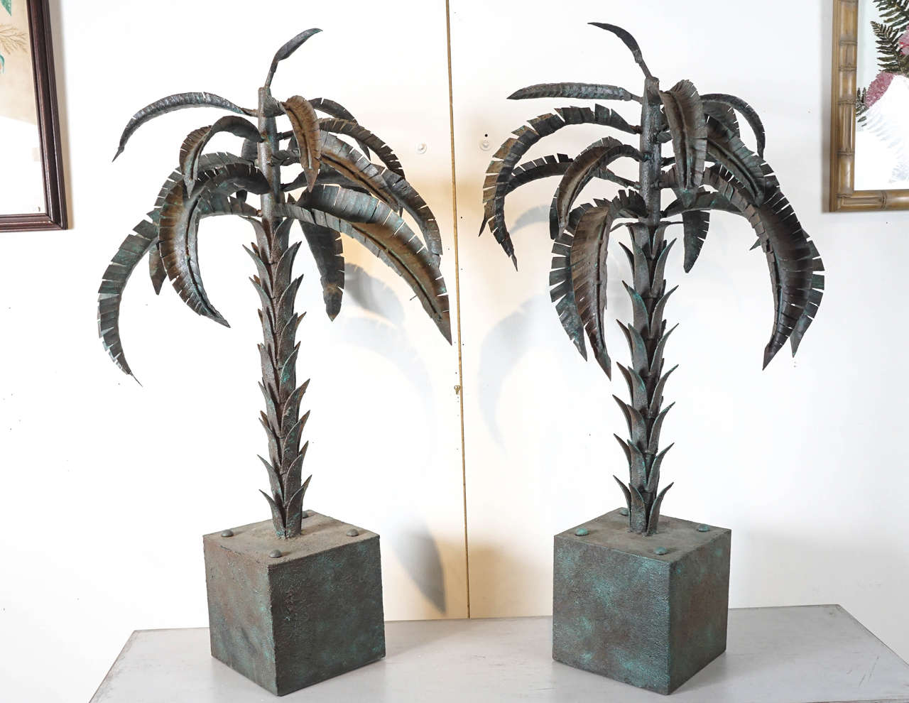 Here is a terrific pair of ornamental palm tree sculptures on pedestals.
In the style of Tony Duquette, the sculptures are made of steel and finished in a textural oxidized copper patina. The palm leaves are form fitted and can be moved around.