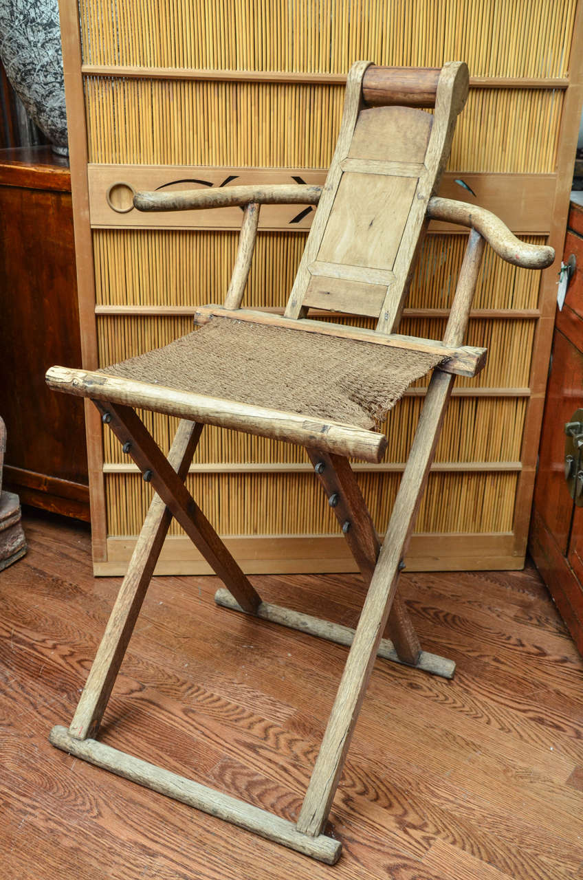 Late 18th century Qing dynasty walnut folding scholar's chair with hemp seat and neck roll.
