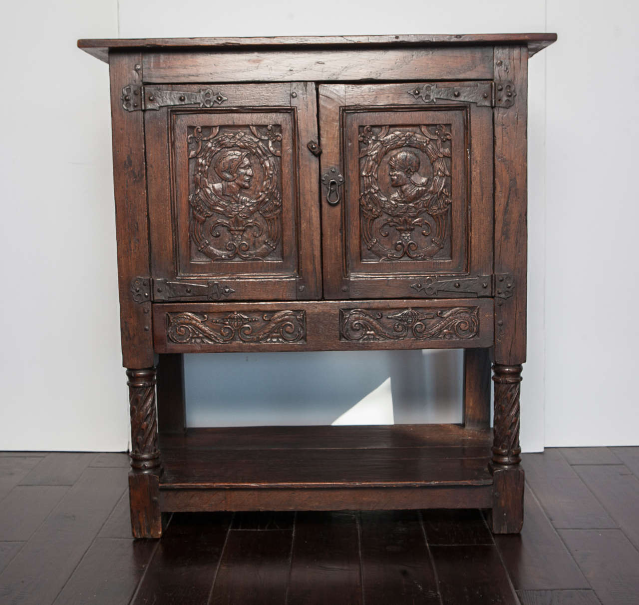 Carved oak cabinet with one interior shelf and one lower shelf.