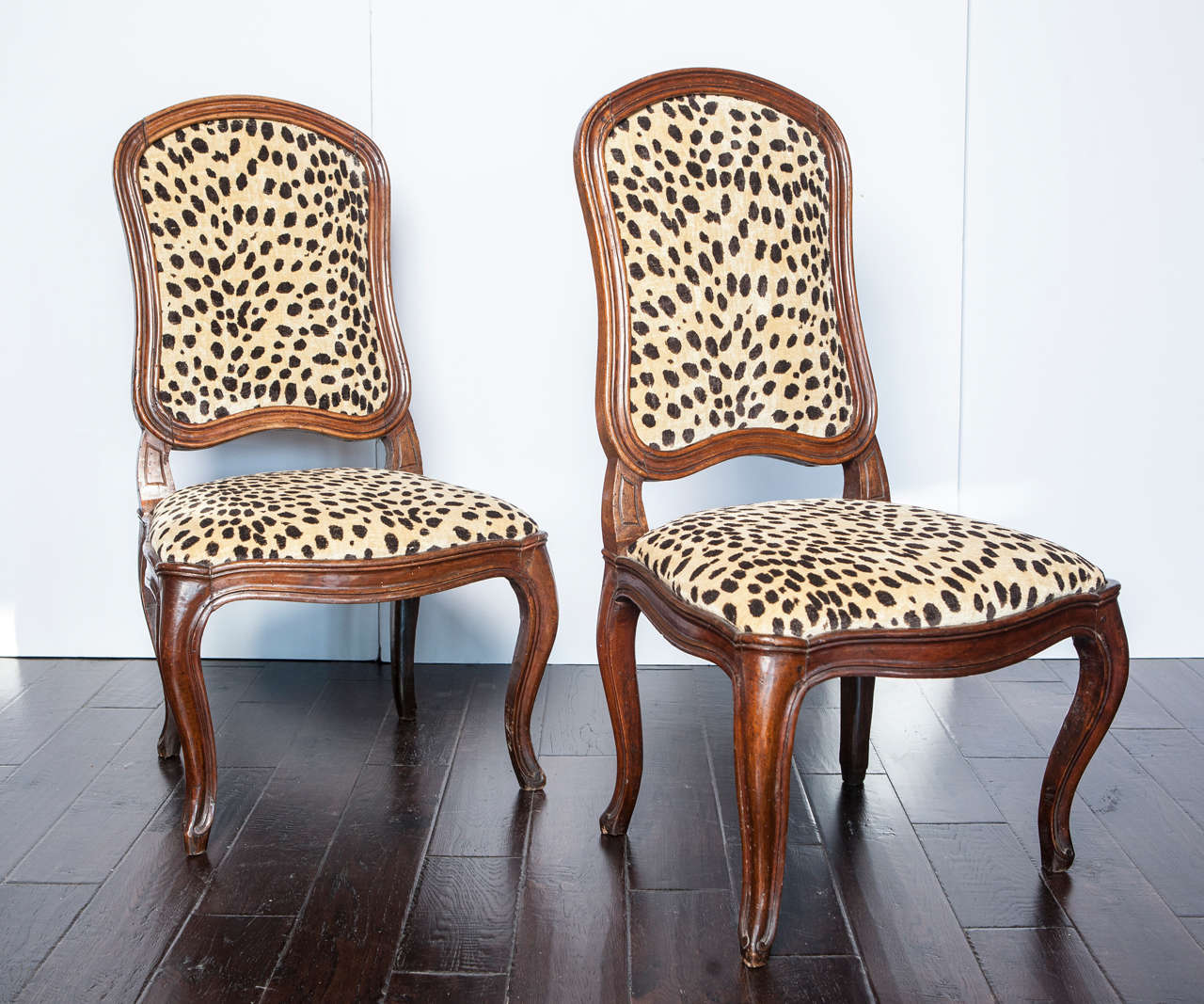 Chairs have carved walnut frames with faux leopard upholstery.