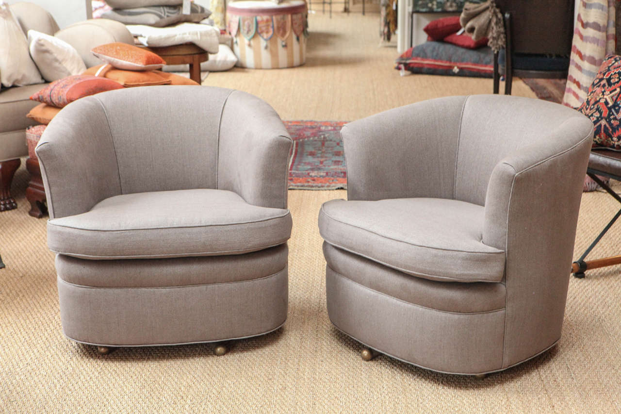 Comfortable barrel back chairs on metal swivel legs.  Reupholstered in contemporary gray linen. Sold as a pair.