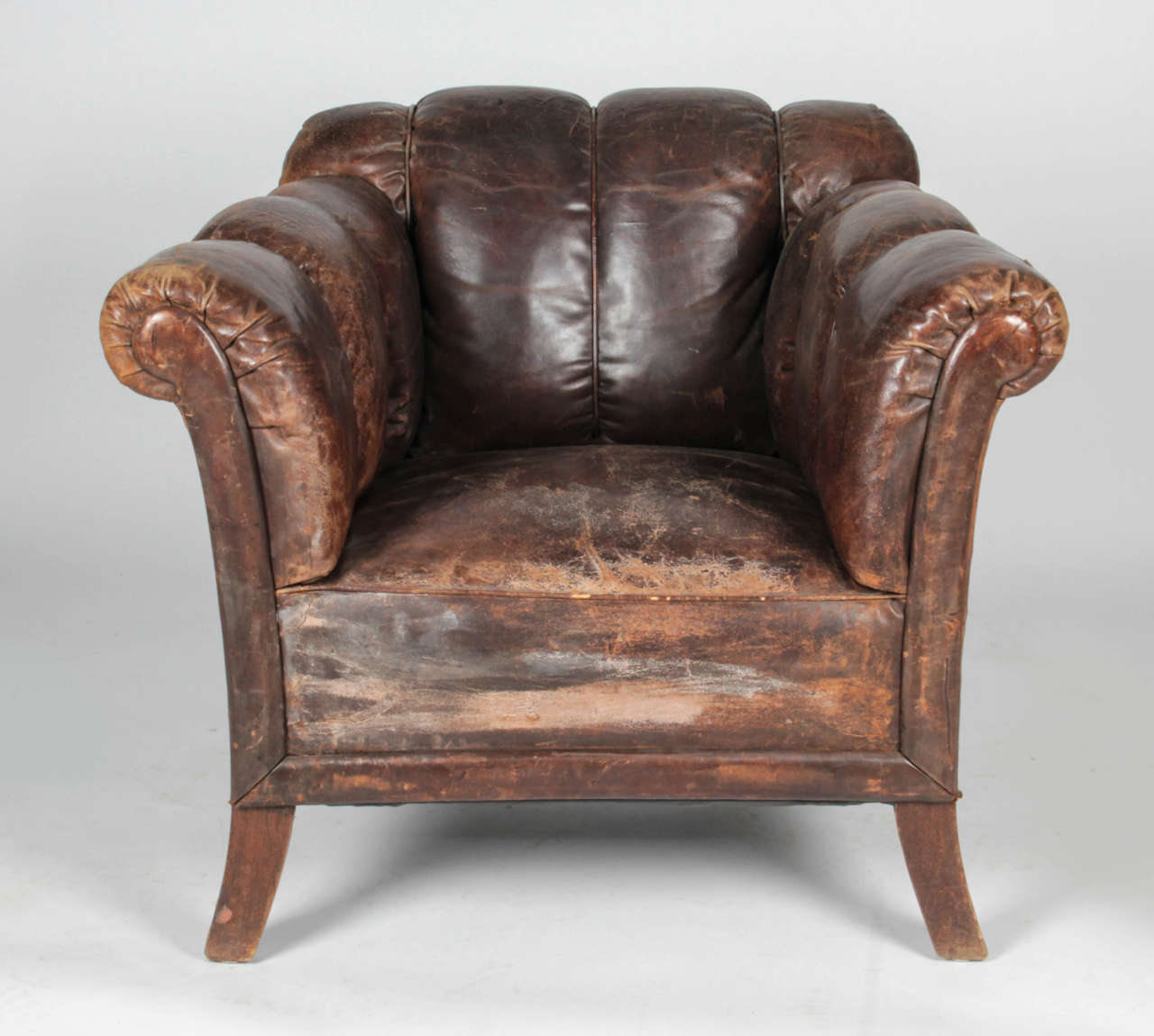 Worn leather club chairs with vertical tufting and piping. Tears in leather on one side and at the back (see pictures). Leather-wrapped nailheads accent the back edges.

Not available for sale or to ship in the state of California.