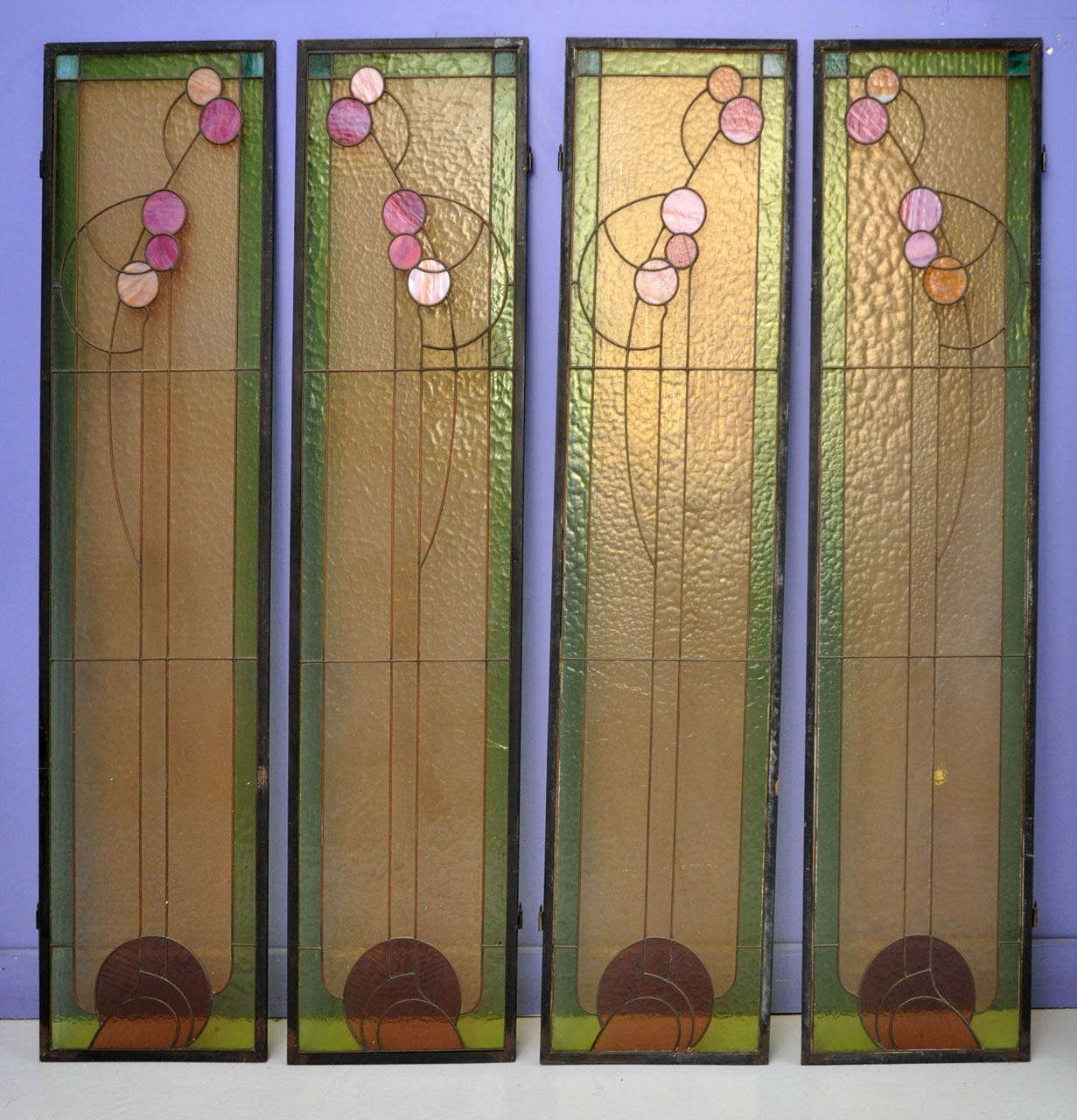 Un ensemble de quatre vitraux Art Nouveau avec de beaux verres d'eau plombés clairs et opaques:: dans des cadres métalliques d'origine. Attribué à Victor Horta.