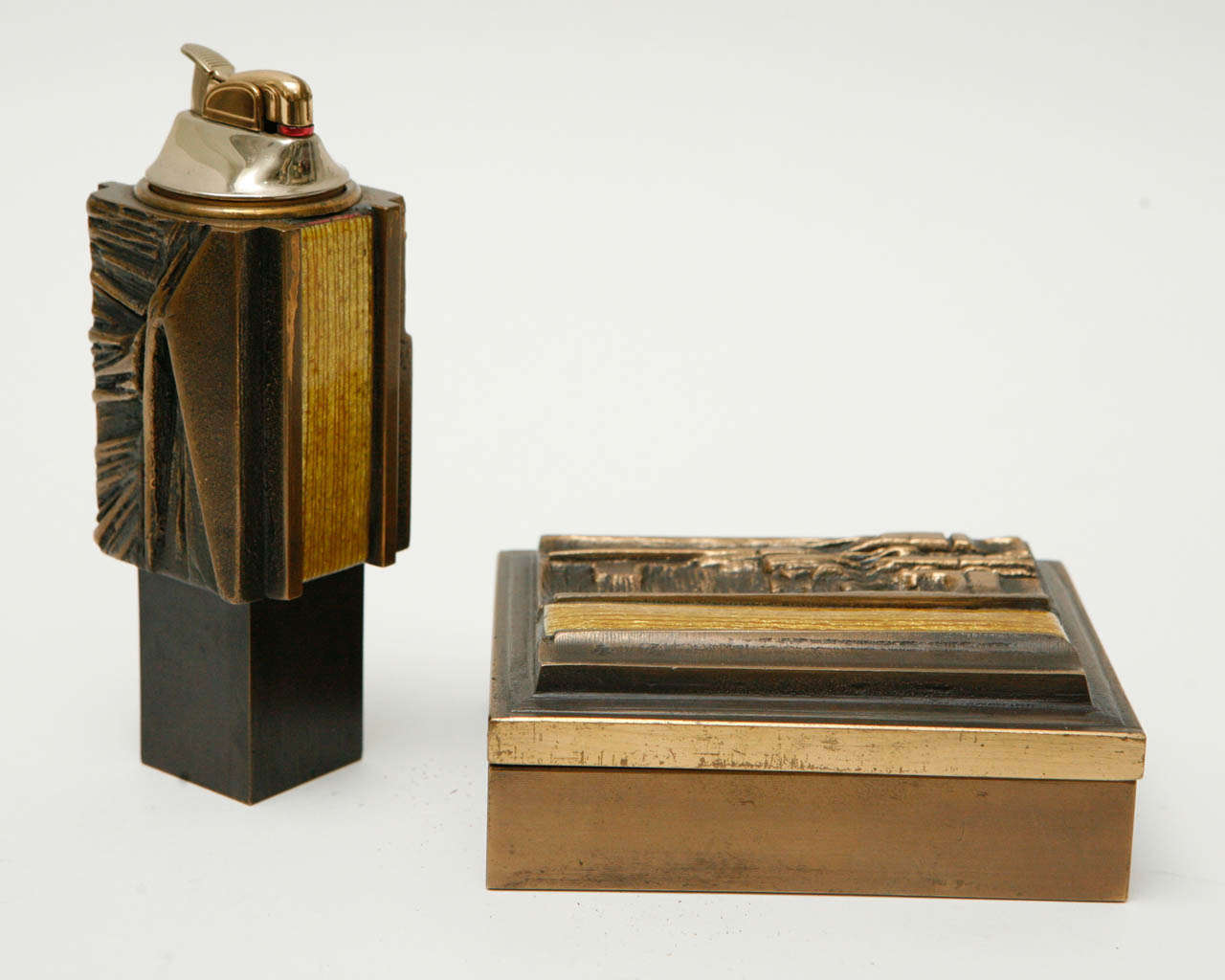 A brutalist-style bronze table lighter and cigarette box accented with gold enamel. Dimensions given below are for the cigarette box, which is signed 