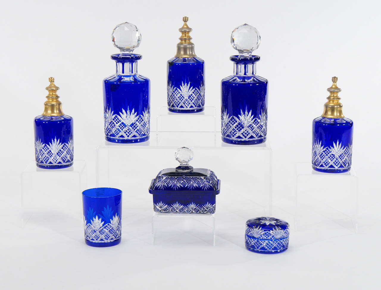 This lovely and complete dresser set, made by Baccarat makes a dramatic statement. The vibrant hand blown cobalt blue crystal is cut to clear to reveal a lovely pattern with clean lines and a modern sensibility. 
The set contains 3 Atomizers (new