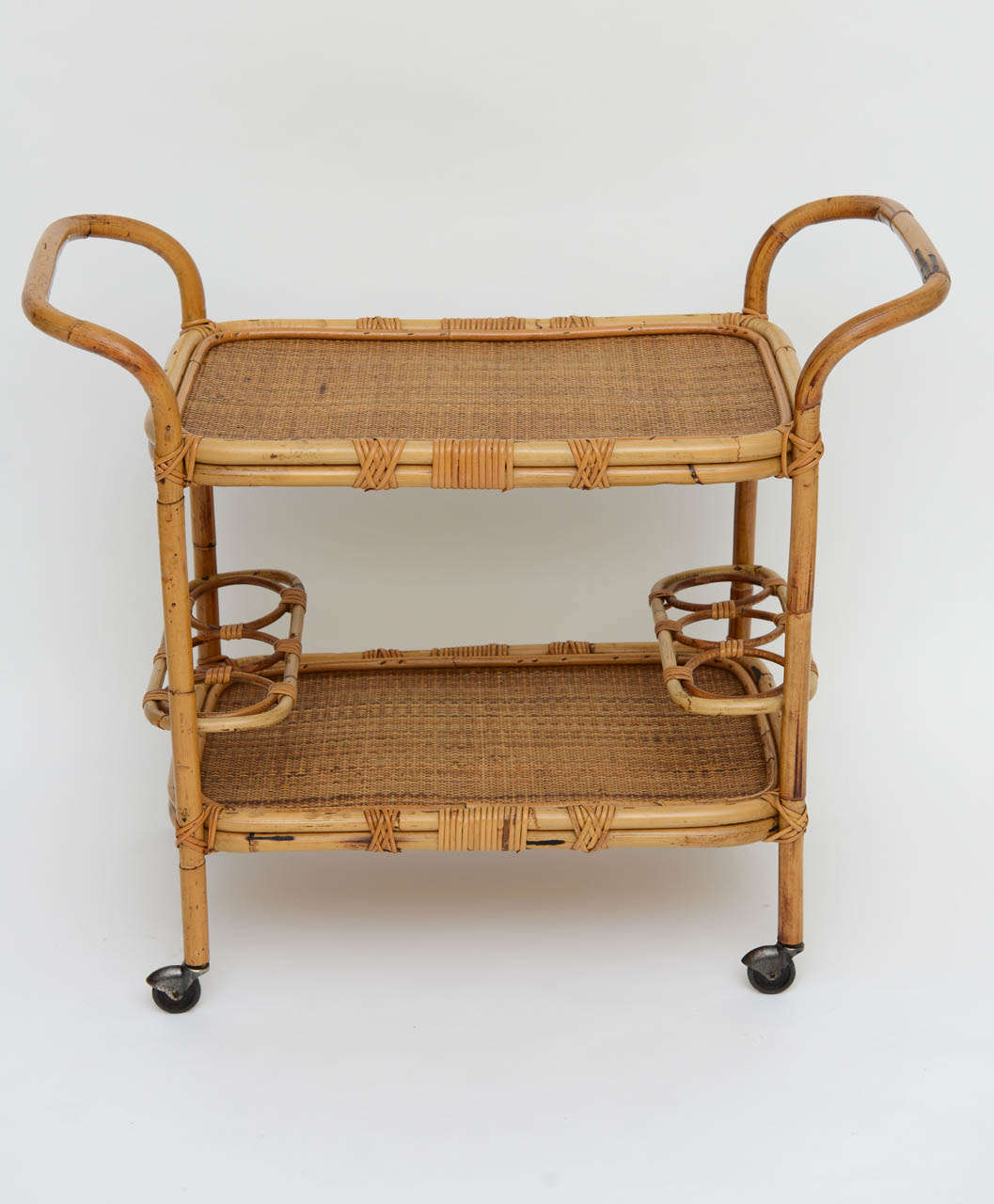SOLD Smart and casual, reminding one of the islands or beach side abode, this rattan rolling cart features two levels of woven caneing and the lower of the two has holders for six bottles.  Great curved rattan handles, all on casters for easy