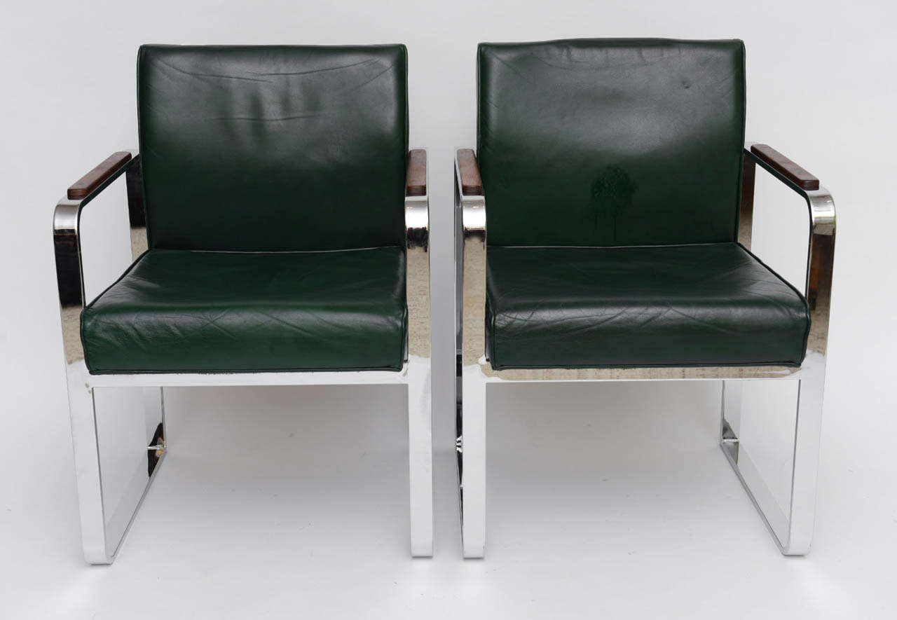 REDUCED FROM $3,500.
Machine age D-shaped arms and legs with green leather upholstered bodies define this pair of armchairs, lounge chairs or club chairs. Sculpted walnut arm pads add posh. In great original condition with small signs of wear to the