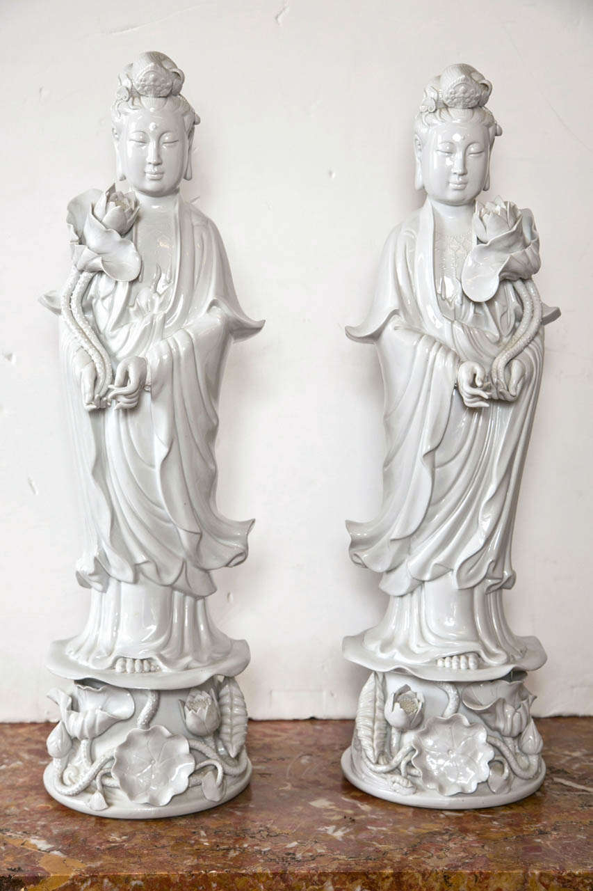 Each figure holding an opening  flower blossom. wearing flowing robes and standing upon a pedestal of  lotus leaves and  flowers. beautifully detailed with  long slender fingers. Possibly figures of G'wan Yin.
Please contact dealer directly.