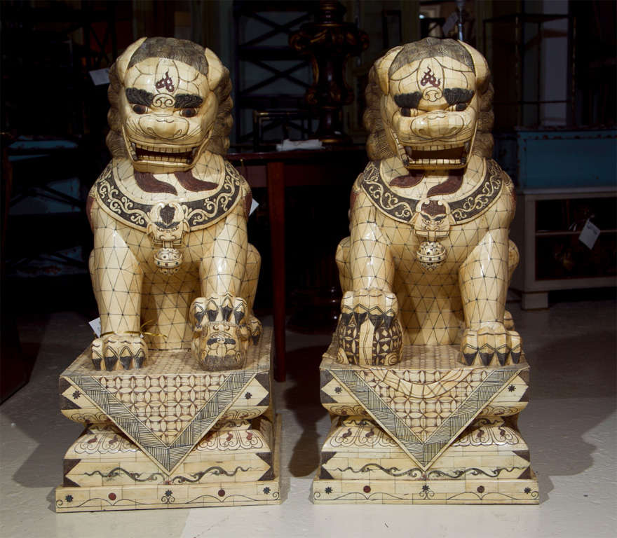 Pair of finely carved palace sized bone and parcel-ebonized Chinese Foo dogs sculptures, both in sitting position raised on platforms. Many pieces missing or loose. 