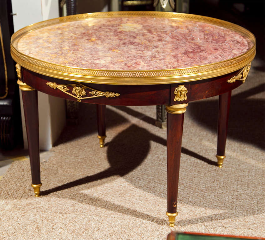 French Empire style mahogany coffee table, circa 1940s, the circular marble with bronze gallery over a round frieze decorated with ormolu figures, raised on circular tapering legs, ending in capped feet. By Maison Jansen.