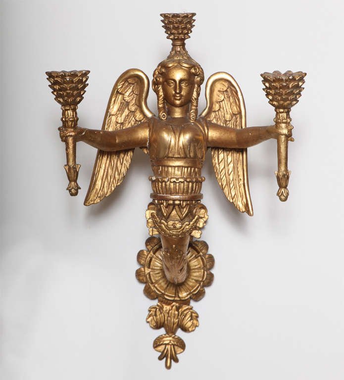 Pair of exquisite Neoclassical carved giltwood sconces, each having draped female figure with wings holding torch in each arm and one on her head, serving as the three candlearms,  extending from backplate of carved floral and arrow motifs.  Not