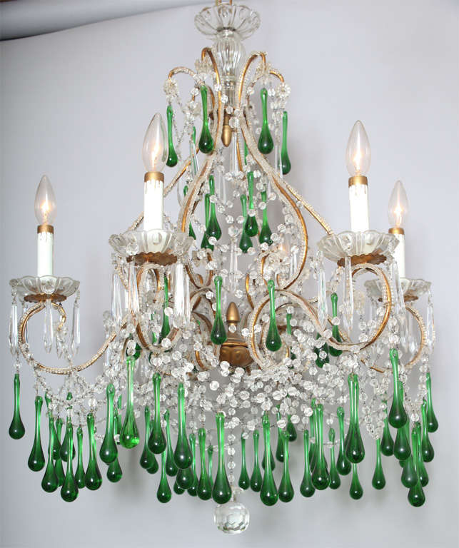 Chandelier, in Maria Theresa style,having a frame of beaded gilded iron, six scrolling candlearms adorned with beading terminate in scalloped glass bobeches, the entire fixure draped in swags of crystal strands, accented by emerald green glass