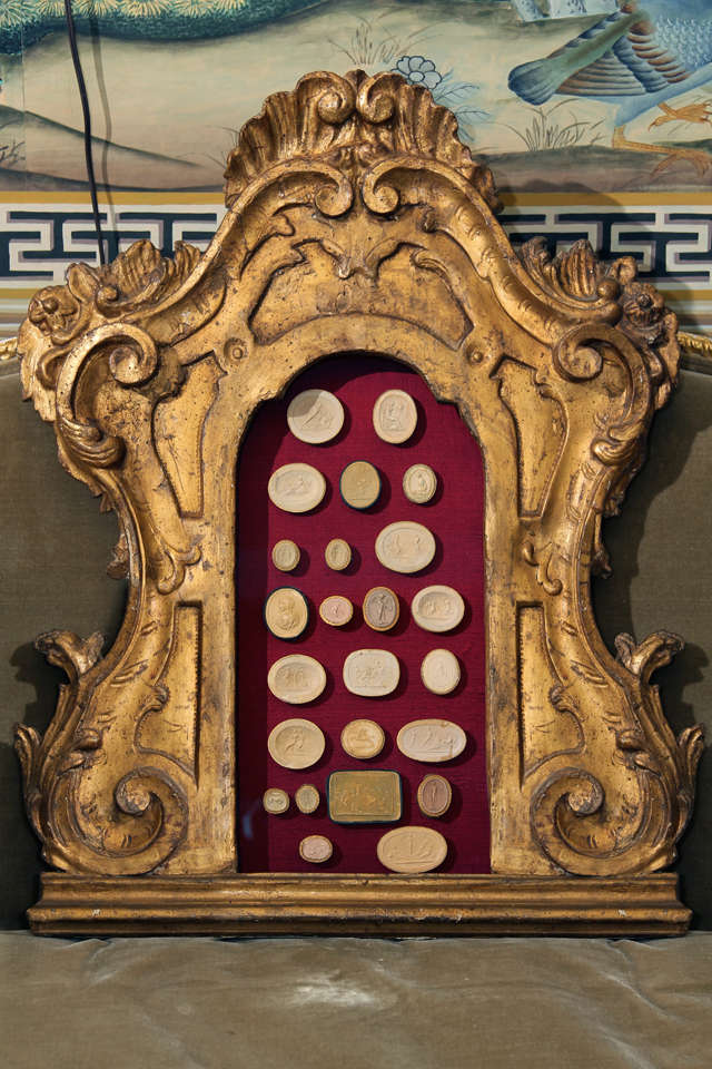 An 18th century Italian carved and gilt frame set with a collection of antique plaster wax seals of a later date.