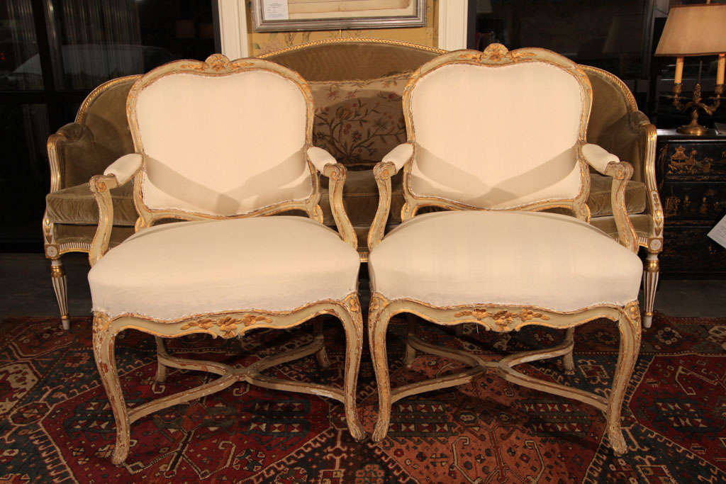 Nice pair of Louis XV arm charis retaining much of the original painted and gilt finish. Upholstered in muslin.