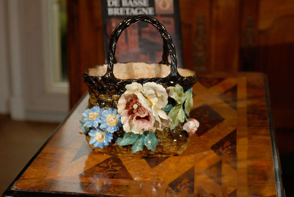 A petite French faïence decorative basket with handles from the 19th century, adorned with a barbotine décor of flowers. This French barbotine basket features a dark brown body with lighter accents, imitating the texture of wicker. The shape is