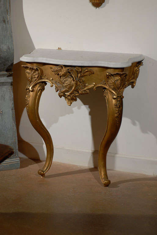 A French Rococo Revival console table with Carrara marble top, giltwood base and stag carving from the mid-19th century. This French console table was born in the 1850s, at a time when the first President of France, Louis Napoléon Bonaparte,