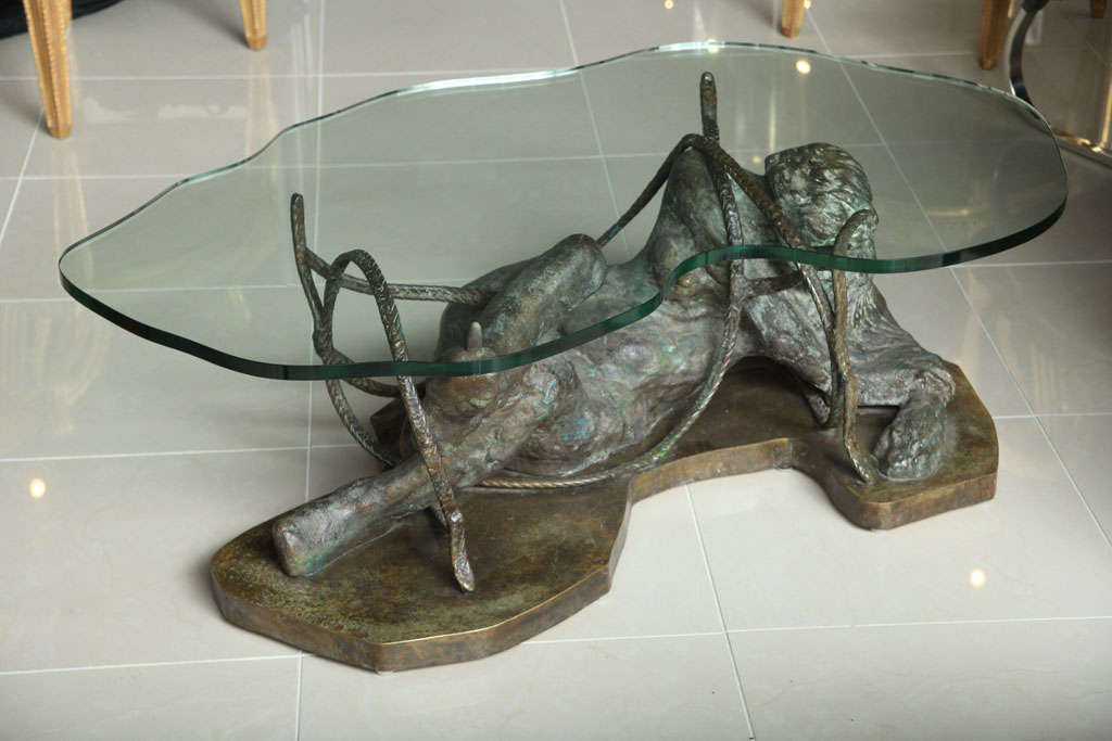 The shaped glass top above a bronze figure intertwined with rope- signed Philip and Kelvin LaVerne.