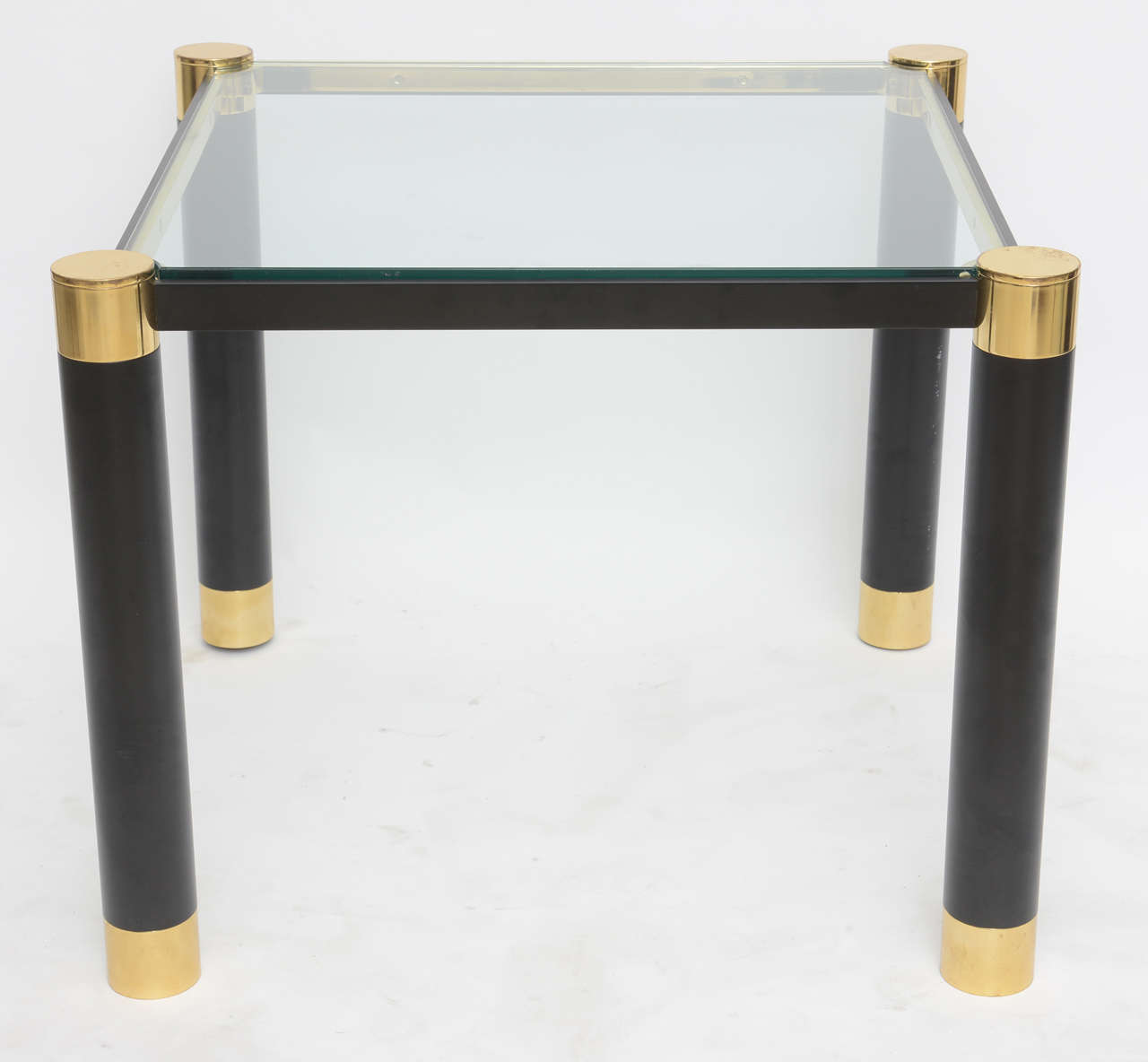 The inset glass with four legs with brass cylindrical tops and ebonized metal legs terminating in brass caps, joined by ebonized metal stretchers,
provenance, Lobel Modern and authenticated by Mary Forsberg, ex director of Karl Springer limited.