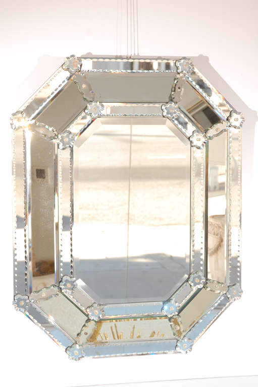 A glittering elongated octagonal Venetian mirror with fancy cut glass and rosette details. Desirable light antiquing to the mirrored glass on the frame.