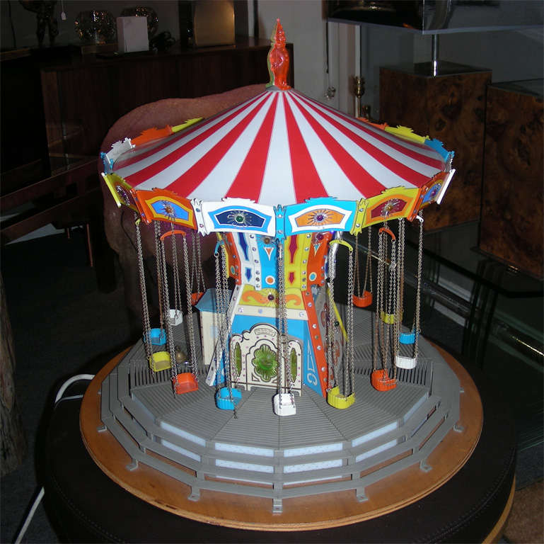 1960s electric merry-go-round on a wooden base, with plastic elements. Electric system lights it up and makes it go round; these two actions can be done together or separately.