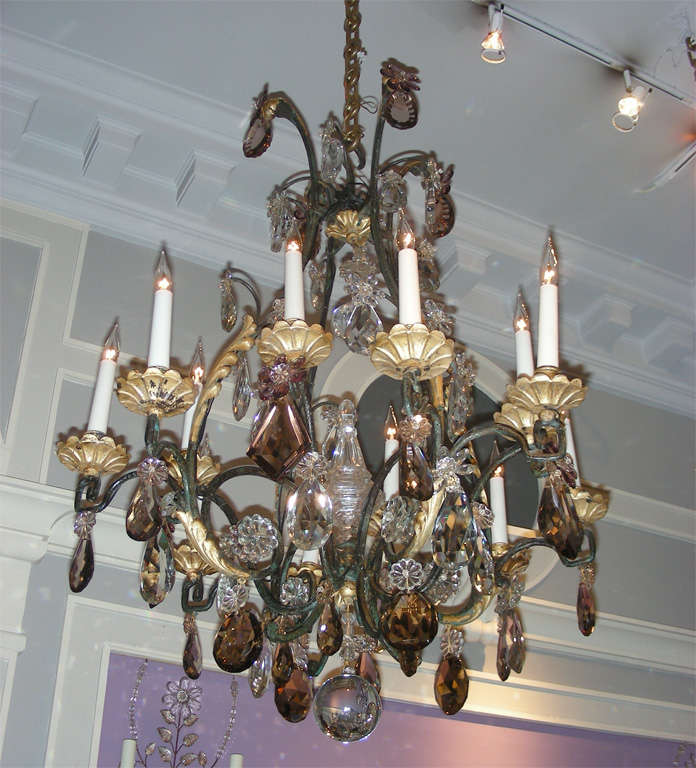 1920-1930 chandelier attributed to Maison Bagues in black and gilded patina wrought iron and crystal drops, clear and colored. Twelve branches.