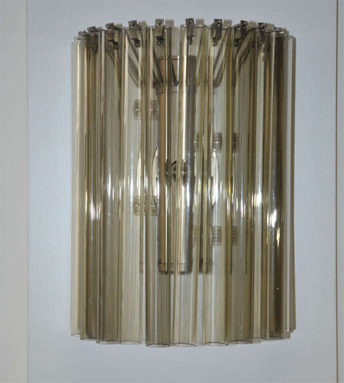 Two rare wall lights produced by Venini, glassworks located in Murano (I). Each made of a chrome-plated fixing and fifteen tubes in light yellow and grey/brown glass. Five fittings for bulbs.
Both with stamped signature on the frame. Listed as model
