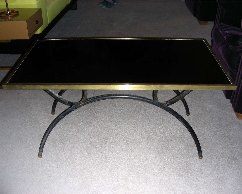 1940s coffee table by Jacques Adnet, with base in black metal and gilded brass balls; top surface in black opaline edged in gilded brass.