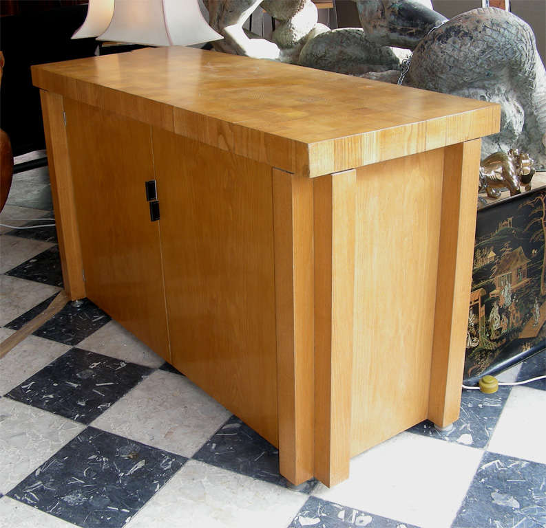 1940-1950 light oak buffet with two doors; top surface made with assembled wood squares; leather handles; four interior shelves in mahogany veneer.