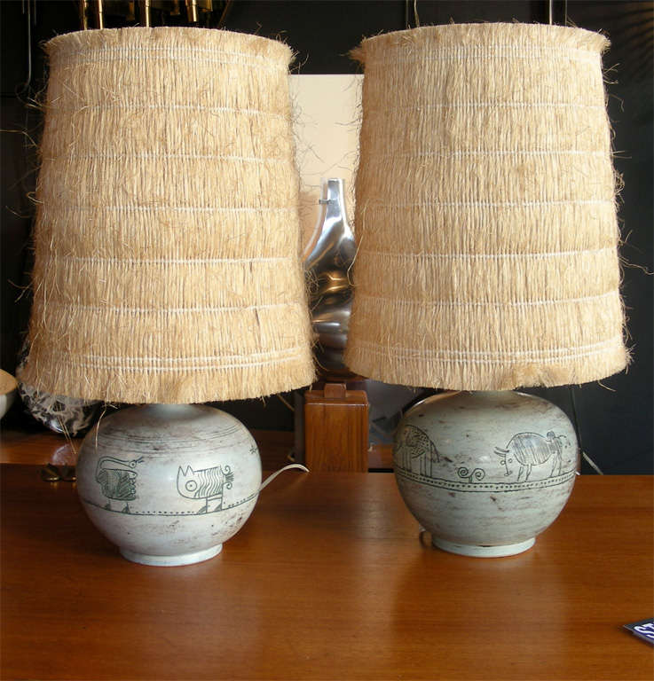 Two ceramic table lamps with an animal design.  The straw lampshades are recent.