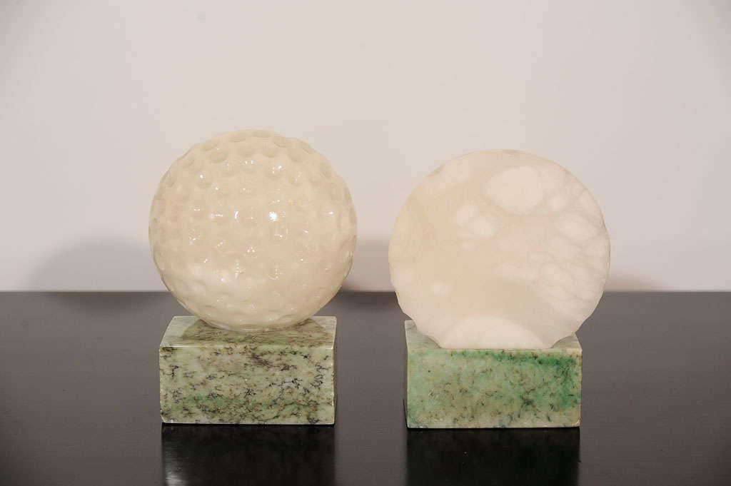 White and green carved alabaster bookends in the form of two half golf balls.