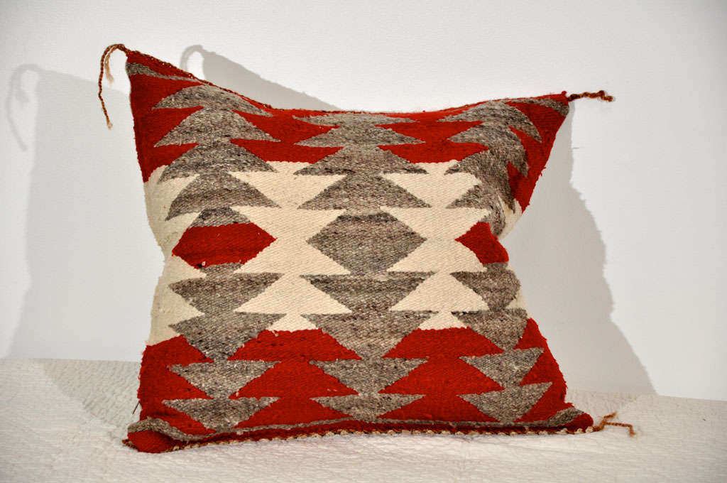 20TH C. NAVAJO INDIAN WEAVING PILLOW WITH HOMESPUN LINEN BACKING. DOWN FEATHER INSERTS. TRIANGULAR PATTERNS ON FRONT OF PILLOW. COLORS ARE RED, CREAM AND GREY.