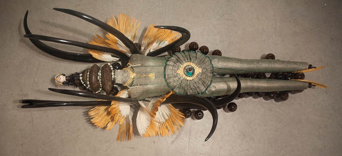 Integrating traditional, antique and synthetic objects and materials found in West Africa, India and America, Banerjee presents a figure clothed in an antique Indian sari sewn with thread made of silver who rests upon glass medicinal bottles.