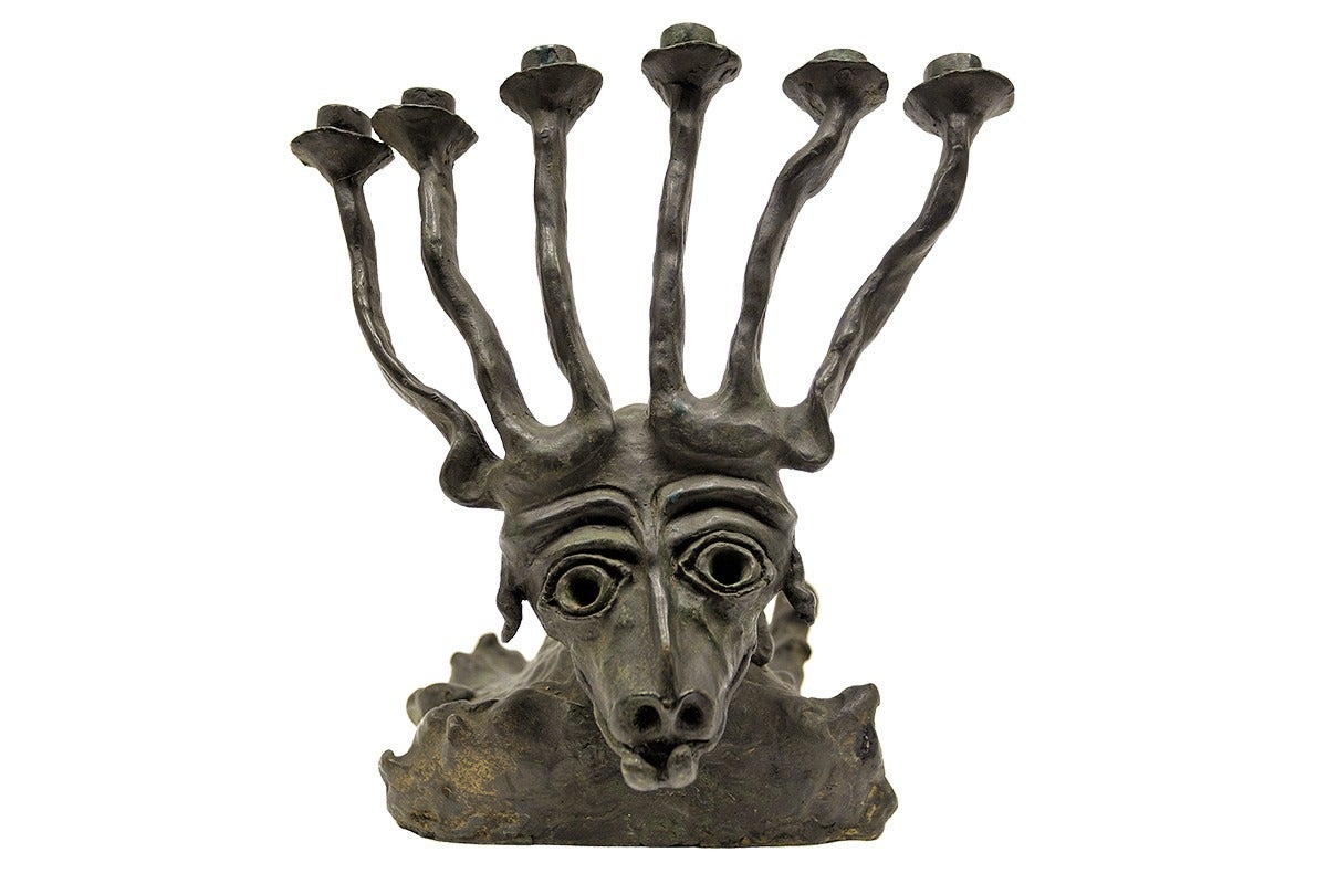 This patinated bronze sculpture by Moshe Oved is a member of the series of Jewish ritual objects that define his oeuvre. The sculpted rams head branches into a memorial Menorah candelabra antlers with six points symbolizing the six million Jewish