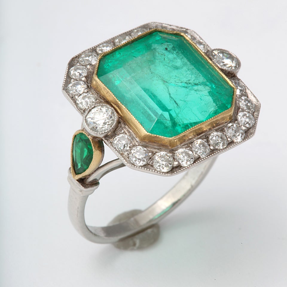 A stunning Columbian 8 ct  Emerald stone surrounded by minecut diamonds and flanked by emeralds on a platinum