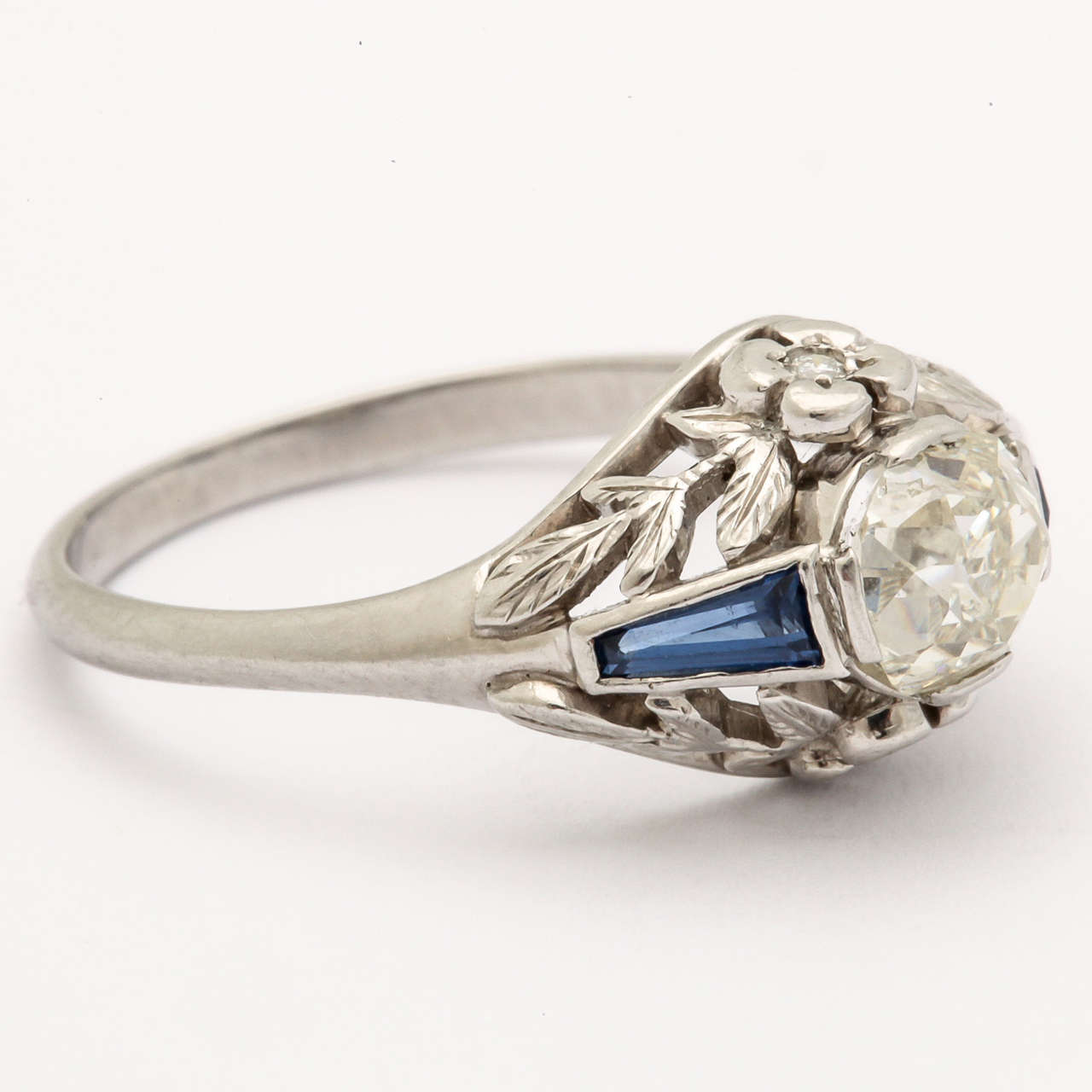 This gorgeous antique deco style platinum ring will give you years of wear and transition into a family heirloom. The old mine, cushion  cut diamond is .89 ct with a beautiful sparkle. On either side of the center stone are specially cut tapered