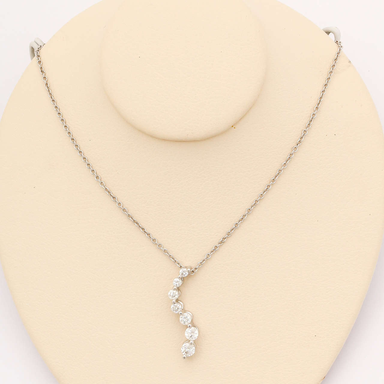 Symbolizing 'Love's Journey',the 7 diamonds, graduating from the smallest to largest are arranged in an eye-catching curve.It is made of 14 kt white gold.
The pendant is suspended from a 16 in., 14 kt white gold cable-link chain made in Italy. A