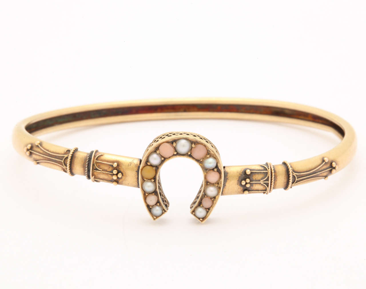 The beautifully executed details are typical of the goldsmiths of the Victorian era. The bracelet is 14 kt gold and the horse shoe is decorated with angel skin coral cabs and half pearls. The delicate bracelet opens with a spring action and fits an