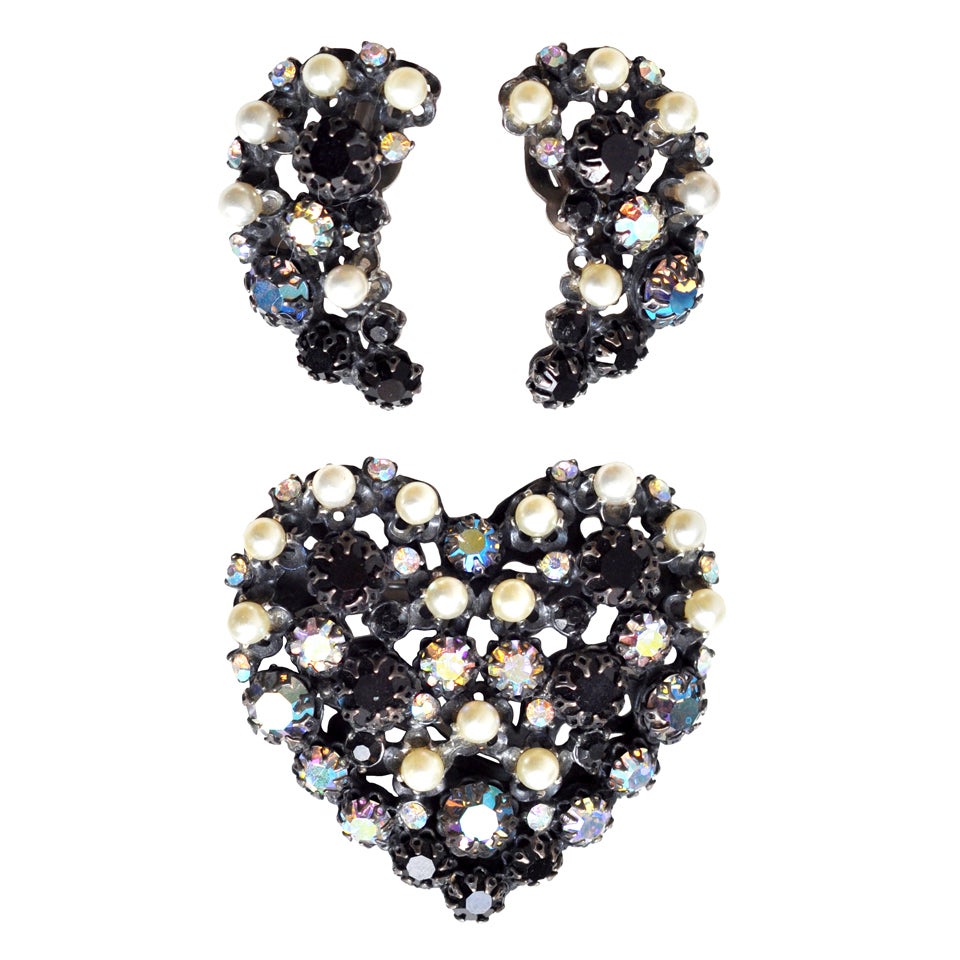 Demi-parure set consisting of a heart-shaped, sculptural brooch and clip earrings by couturier Elsa Schiaparelli. Schiaparelli was known for her high quality costume jewelry and innovative combination of stones. All pieces are signed.  A beautiful,