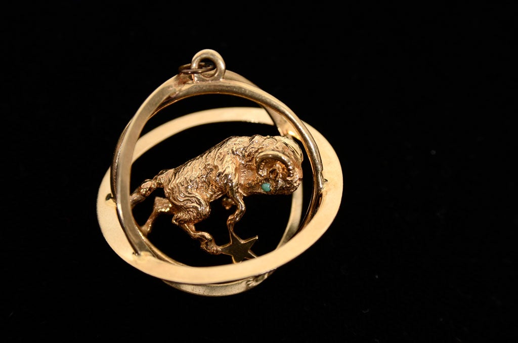 This very three dimensional 14k yellow gold charm features three  concentric rings symbolizing the world with a Ram with turquoise eyes standing on a star floating in it.This would be a great addition to a charm bracelet or just great worn on a