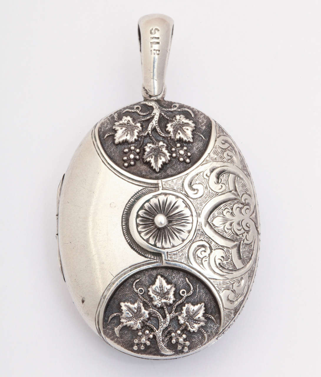 Handsomely engraved on both its sides, this English silver locket is a model of the fine silver work created in the late 19th century in the United Kingdom.  Jewelry at that time reflected the nature, whimsy, sentimentality and symbolism. One side