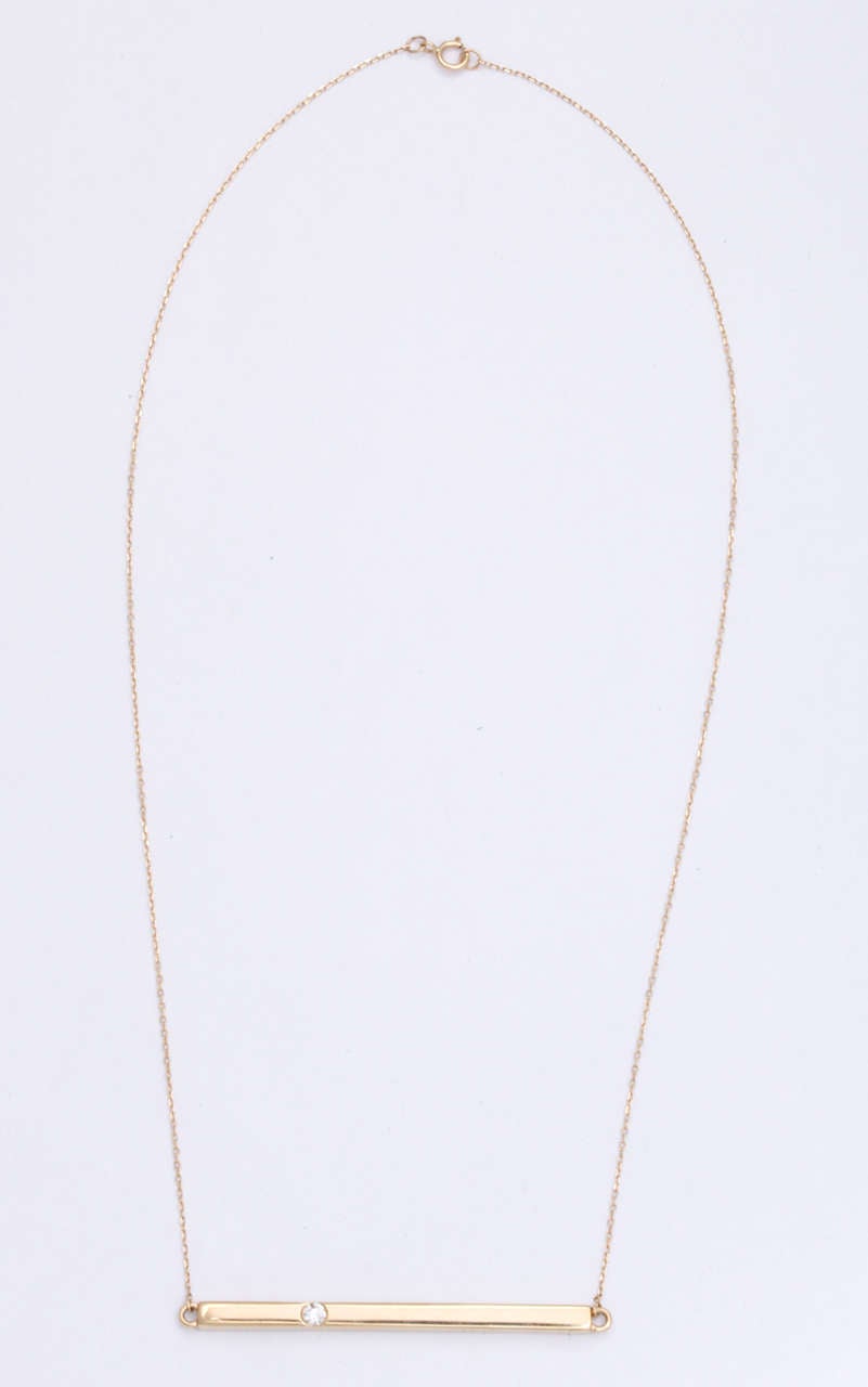 14K Yellow gold bar necklace featuring one round diamond, 0.10 carats.