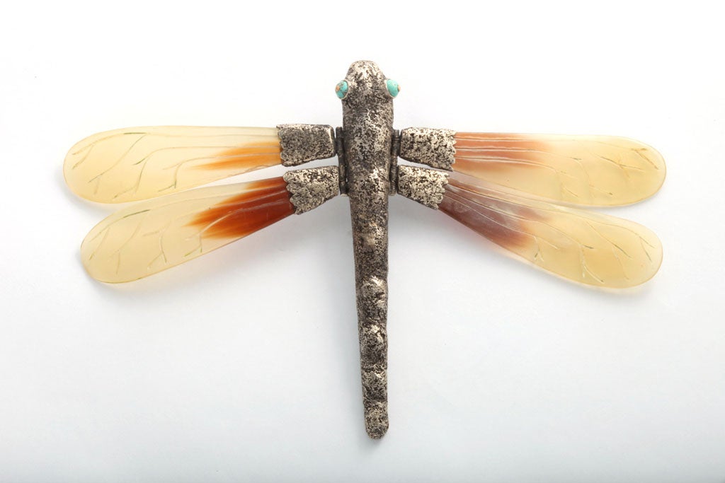 A unique dragonfly pin. The sculpted sterling body and hinged wing attachments hold large translucent carved horn, movable wings. An extraordinary piece!