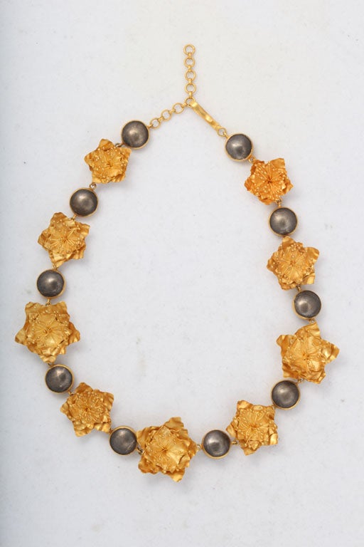 A flower necklace composed of nine 18kt yellow gold flowers interspersed with sterling silver beads that have been bezel set with 18kt yellow gold. The necklace can be wrapped around the wrist twice and worn as a bracelet.
Length: 15 inches
Width: