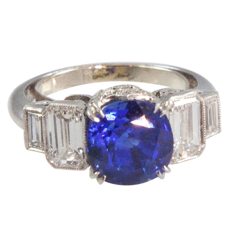 The ring centers 1 four prong-set cushion mixed-cut sapphire flanked by 2 bezel-set rectangular diamonds (all stones circa 1910) on either side in a contemporary mounting desinged with triangular motifs bead-set with small round diamonds. Total