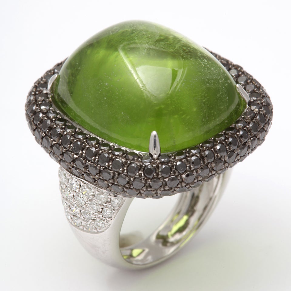 18k white gold ring featuring a massive cabochon peridot 22 x 18 mm  34.60 carats.  surounded by 208 black diamonds 3.28 carats and 42 white diamonds  .65 carats