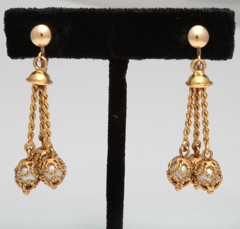 a great pair of 18 kt gold clip earrings with three pearls hanging by and within gold ropes