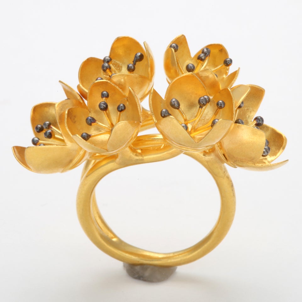 An 18kt yellow gold buttercup ring composed of six buttercup buds. Each buttercup is set with clusters of 18kt yellow gold stamen and rhodium plated sterling silver beads. Size 6.25
Width: 1.50 inches
Flower Height: .50 inch